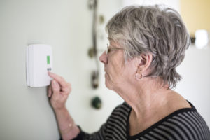 Old woman controlling thermostat